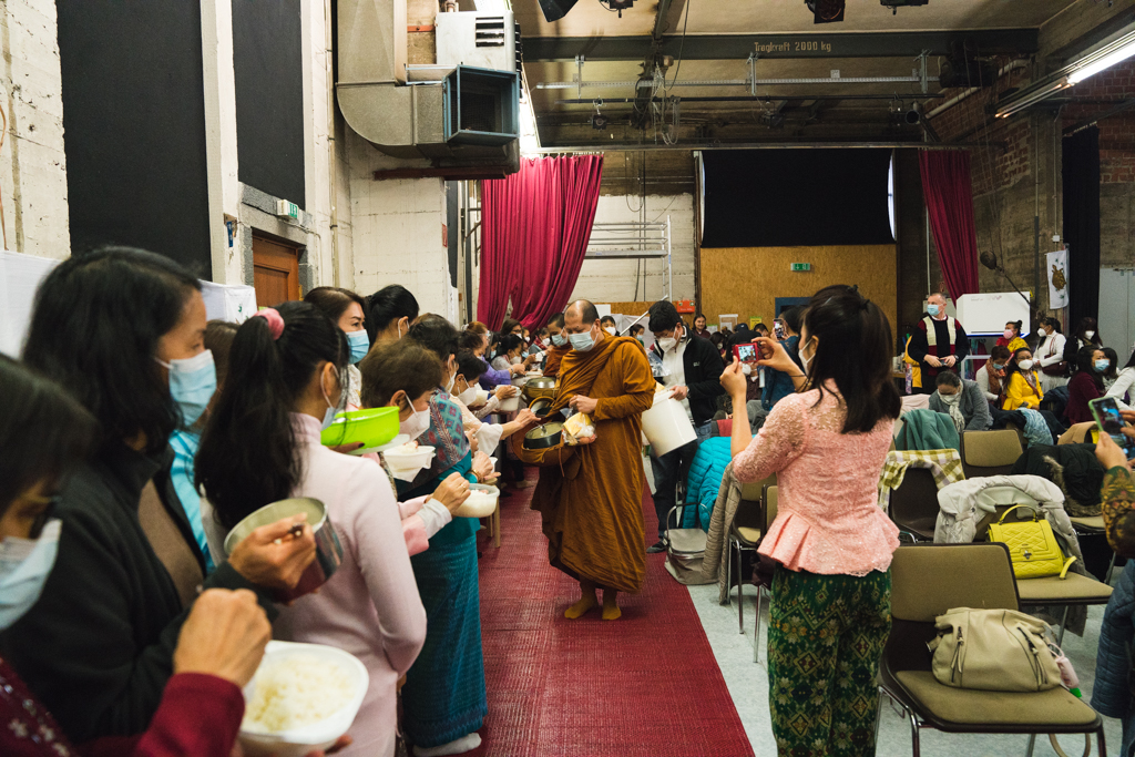 Buddhistische Gemeinde überreicht den Mönchen Essen.